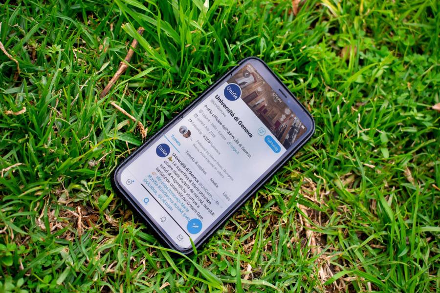 Cellulare sull'erba con schermata su pagina social unige 