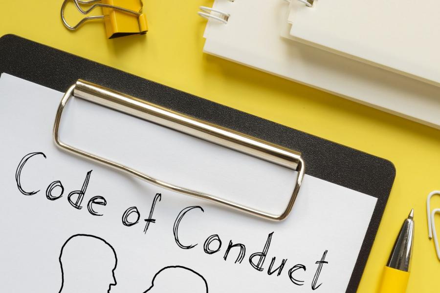 grafica con immagina di un bloc notes su scrivania con scritta Code of Conduct