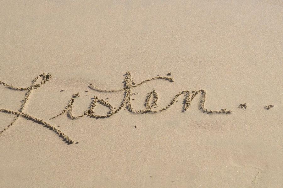 scritta sulla sabbia in corsivo: listen...